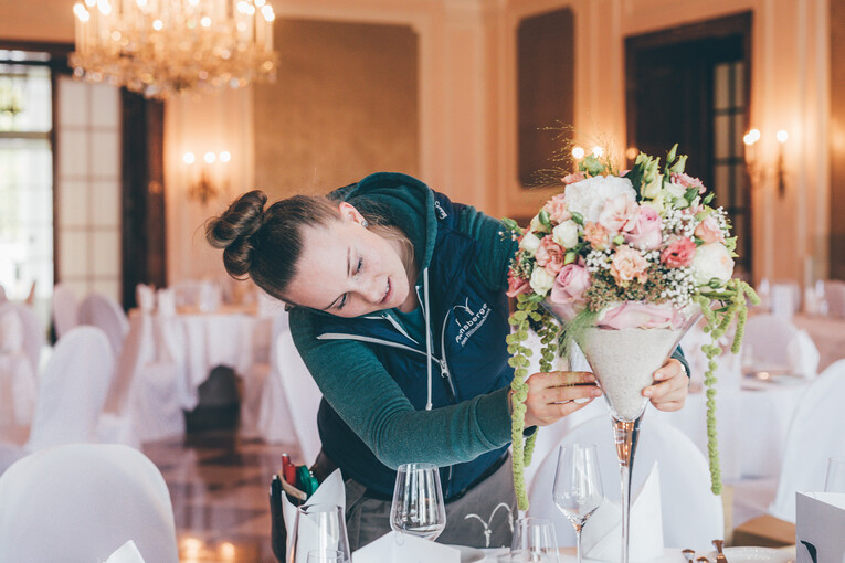 Eine Mitarbeiterin perfektioniert die pastellfarbene Tischdekoration für eine Hochzeit