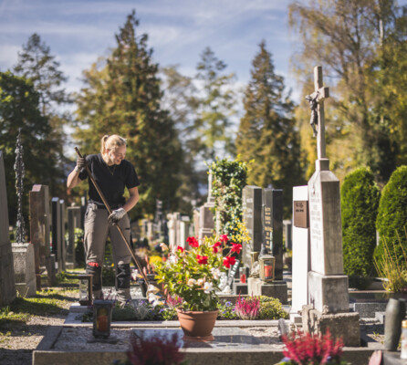 Eine Mitarbeiterin pflegt ein Grab