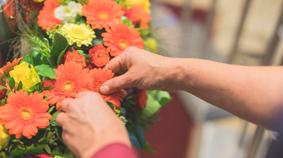 Ein Mitarbeiter steckt einen Trauerkranz in warmen Farbtönen