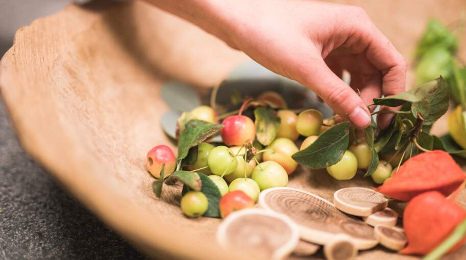 Eine Mitarbeiterin stellt eine dekorative Schale mit Kirschen und verschiedenen Pflanzen zusammen