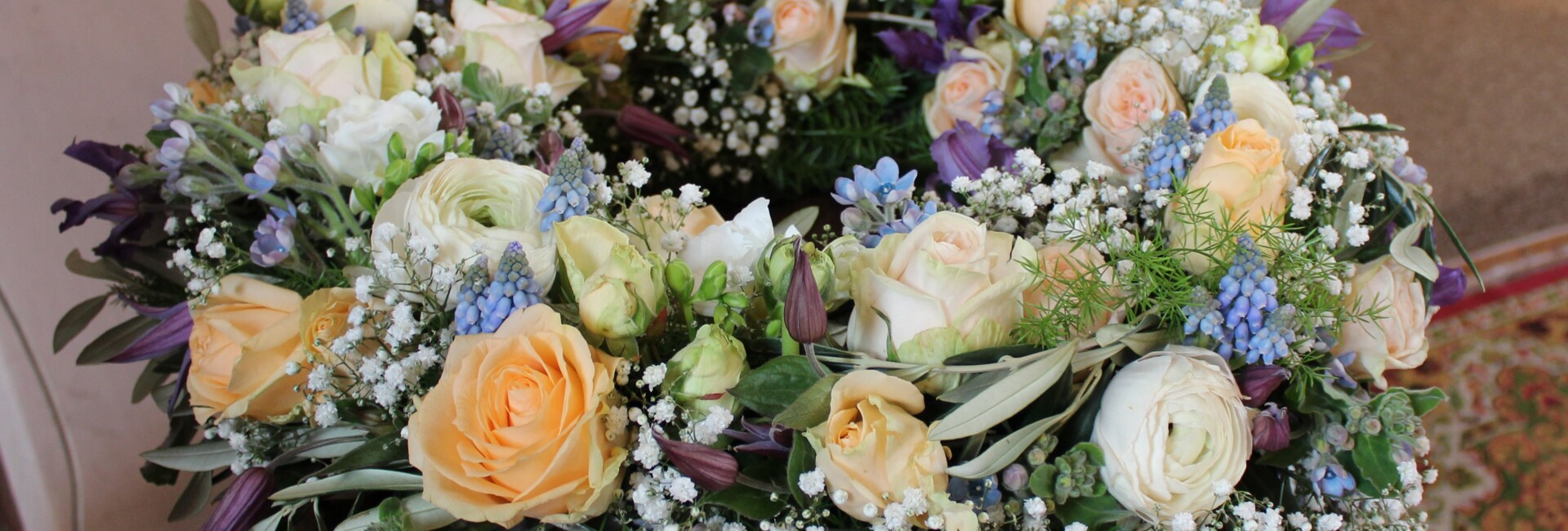 Ein stimmiger Blumenstrauß aus weißen, pfirsichfarbenen und blauen Blüten