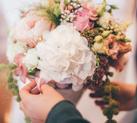 Eine Mitarbeiterin verleiht einem Blumenarrangement aus rosa, weißen und grünen Blumen den letzten Schliff