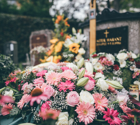 Ein prächtig mit Blumen geschmücktes Grab in Rosatönen