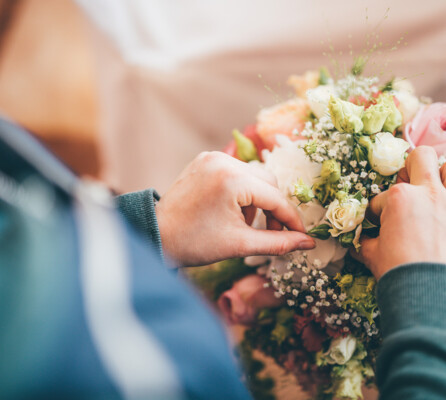 Eine Mitarbeiterin zupft die letzten Blumen eines pastellfarbenen Straußes zurecht