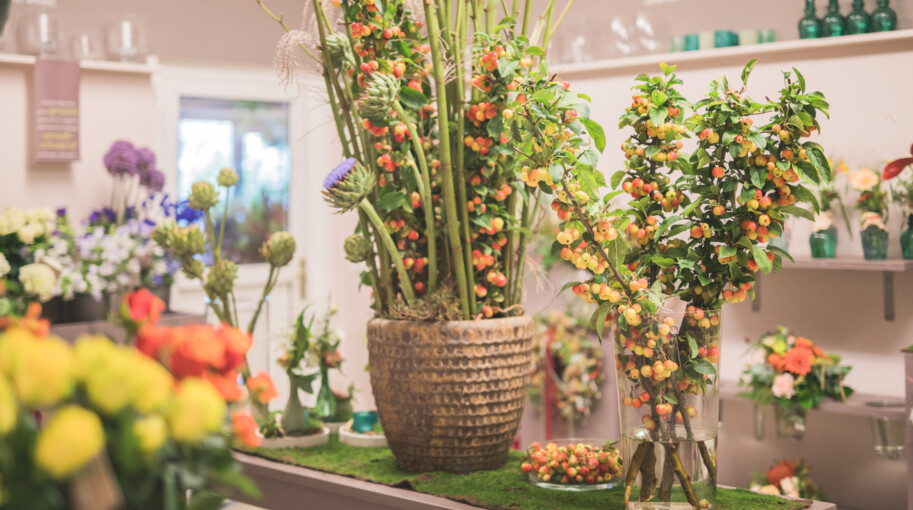 Aufnahme von Vasen mit mehreren Zweigen, an denen orange Beeren hängen