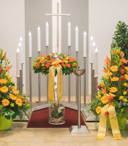 Die liebevoll angerichteten Blumenarrangements in orangen und gelben Farbtönen